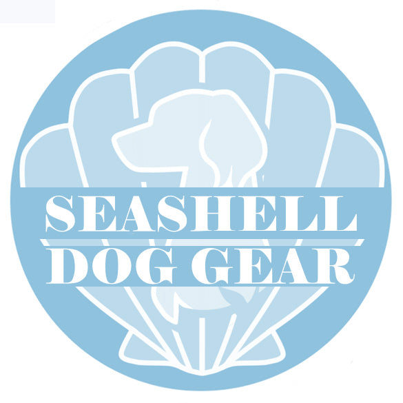 A pale blue circle with an outlined white seashell taking up the majority of the background, in front of the seashell is the white outline of a dog's bust (chest + head), the dog has long furry ears. 'SEASHELL DOG GEAR' is written in two lines across the centre of the circle, also in white.
